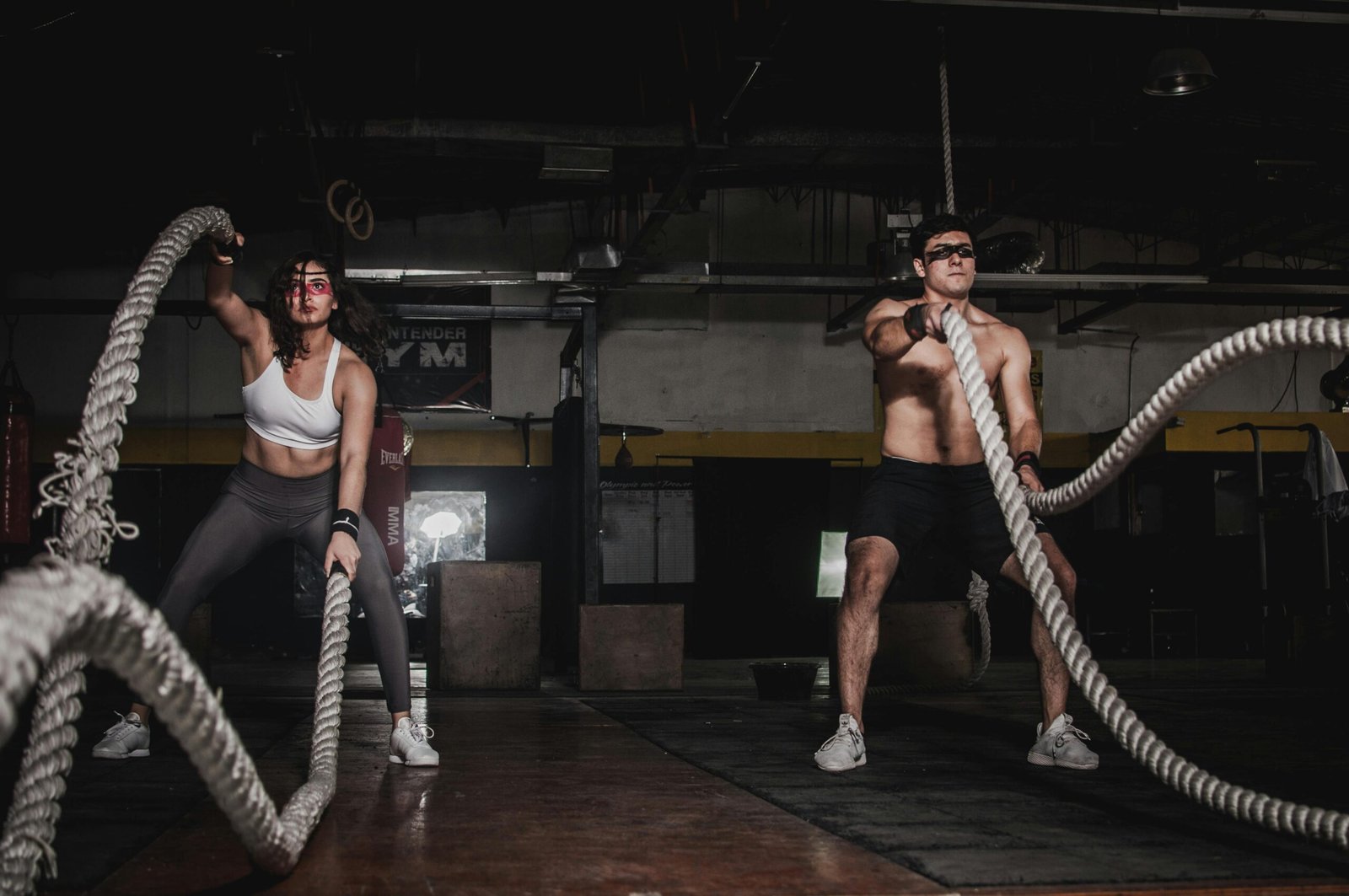 Two people engage in a powerful indoor battle rope workout, showcasing strength and energy.